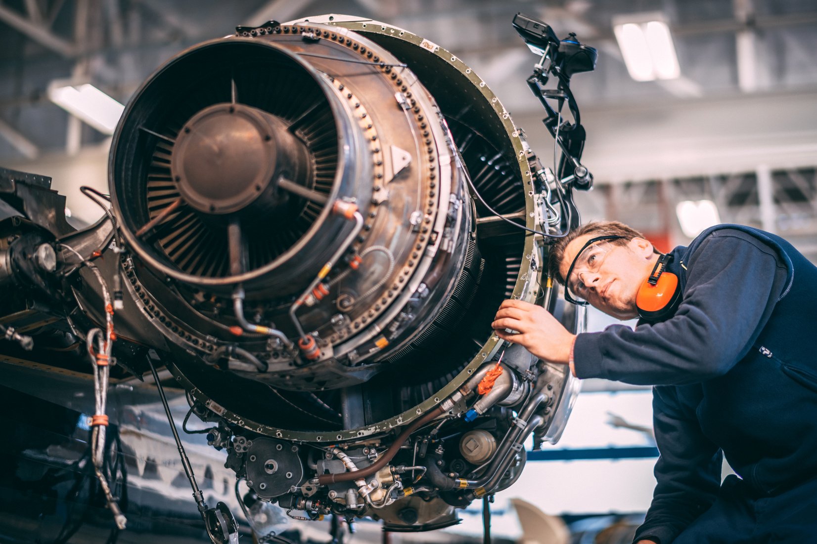 Aircraft engineer repairing and maintaining a small airplane's jet engine in a maintenance hangar